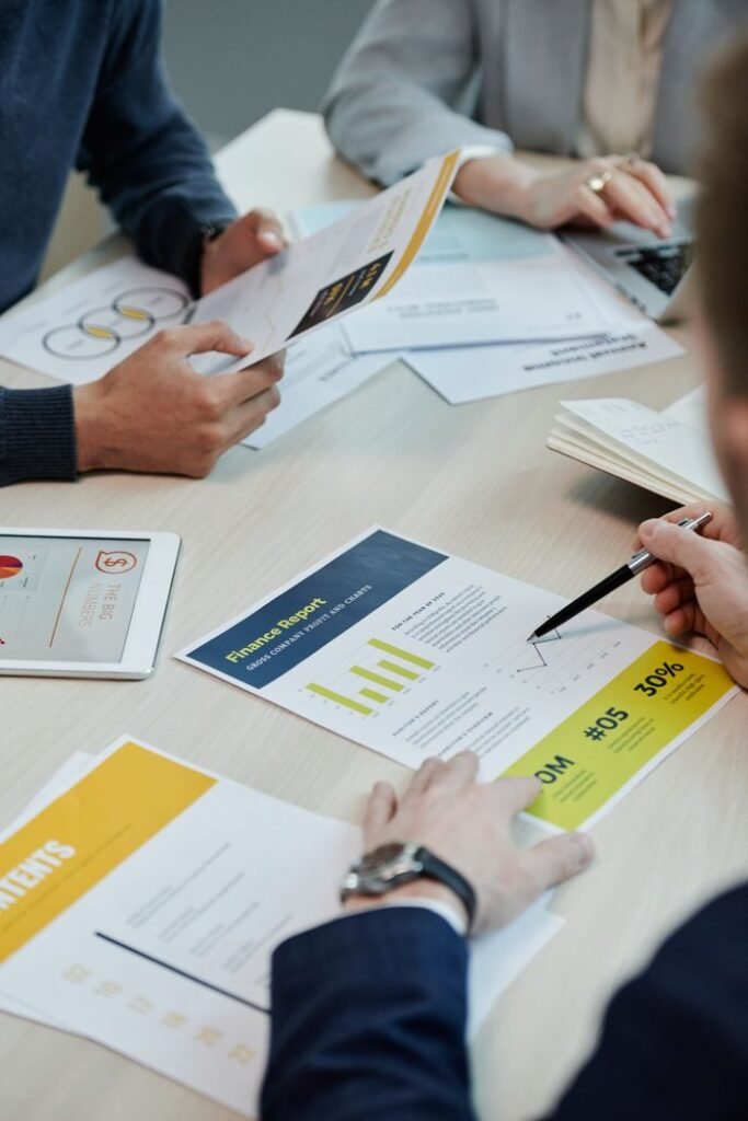pexels photo 7108721 Professionals working together in an office, analyzing financial reports and documents with focus on graphs and teamwork.